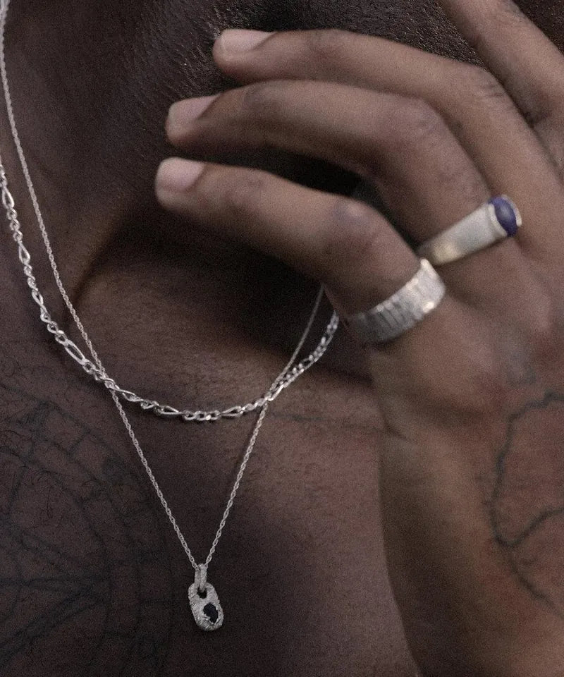 Zwei Silberketten mit Anhänger am Hals, Hand mit Ringen