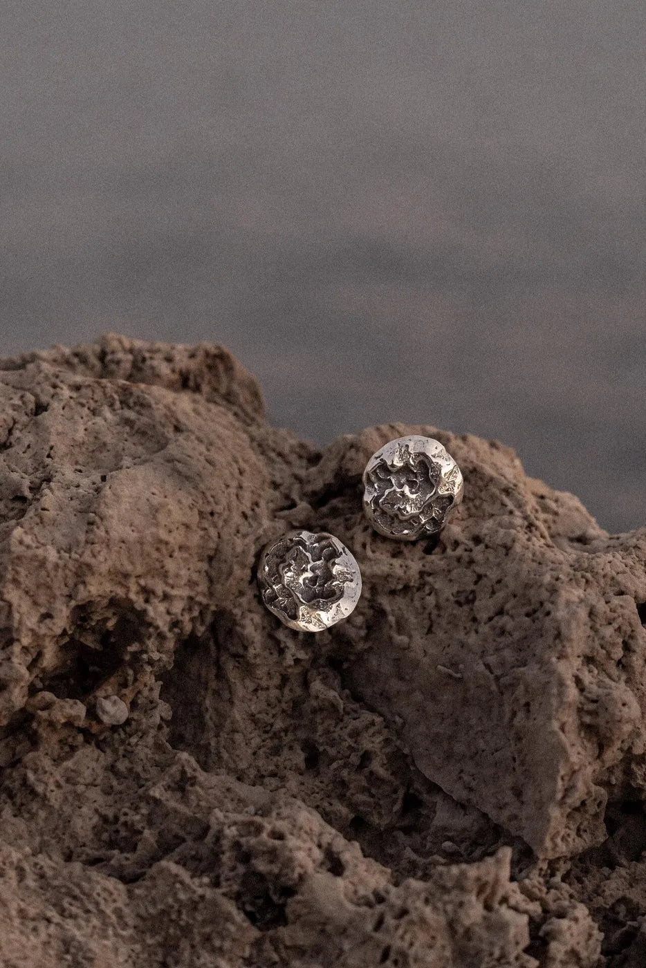 Ohrstecker mit Lava-Struktur auf porösem Stein